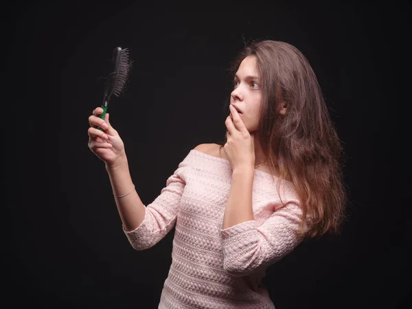 Mujer estresada con problemas de cabello sobre un fondo negro. Vitaminas para el cabello frágil. Concepto de tratamiento capilar. Copiar espacio . — Foto de Stock