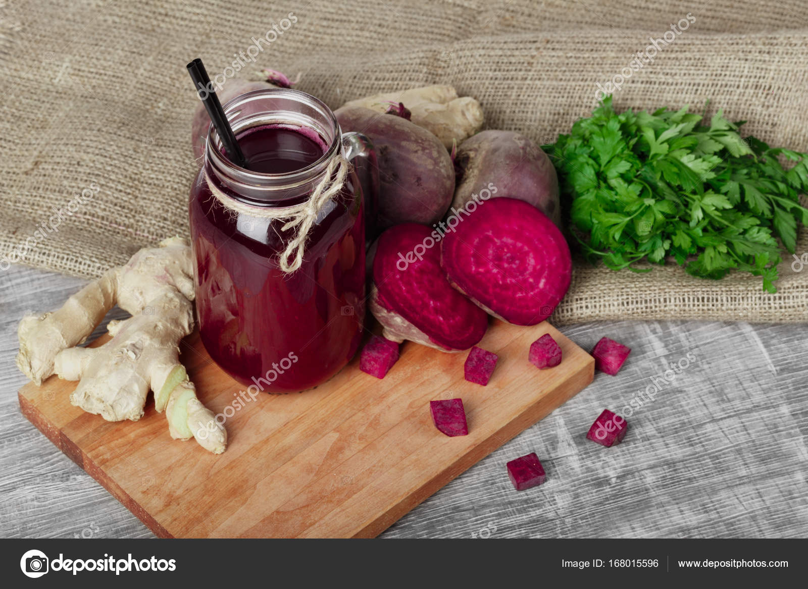 A mason jar of beetroot juice with black straw on a wooden background