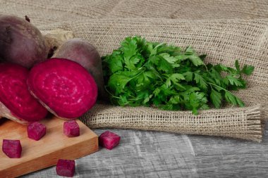 Bütün ve dilimlenmiş beetroots ve taze maydanoz hafif kumaş ve ahşap arka plan. Bir bahçe sebze.