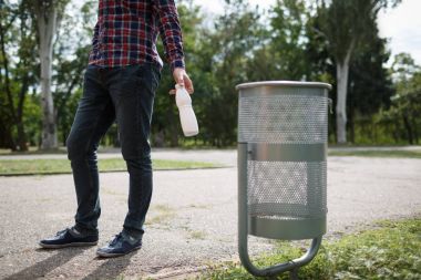 Litttering erkek. Boş bir plastik şişe yol yere çöp içme. Çevre koruma kavramı.