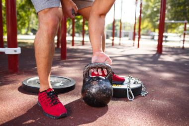 Bir adam kendi ayakları üzerinde egzersizleri yapıyor. Sportif ve sağlıklı genç adam açık havada egzersiz kusursuz bir beden ile.