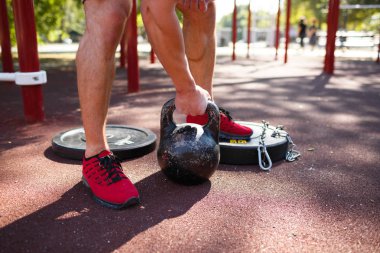 Bir adam kendi ayakları üzerinde egzersizleri yapıyor. Sportif ve sağlıklı genç adam açık havada egzersiz kusursuz bir beden ile.