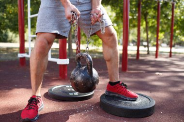 Bir adam kendi ayakları üzerinde egzersizleri yapıyor. Sportif ve sağlıklı genç adam açık havada egzersiz kusursuz bir beden ile.