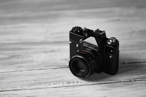 Den gamla manuella kameran på en vit bakgrund på bord av trä. Professionell svart kamera. — Stockfoto