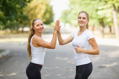 İki mutlu, güzel kız spor giyim doğal bir arka plan üzerinde poz. Dostluk kavramı. Kopya alanı.