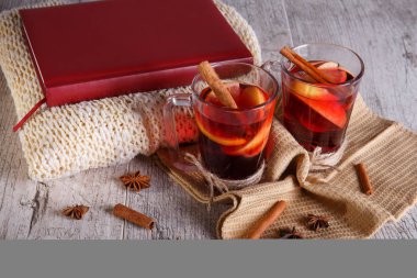 Tarçın ve kırmızı kitap üzerinde hafif bir arka plan üzerinde bir eşarp ile limonlu çay. Sıcak içecekler. Rahat ev atmosfer.