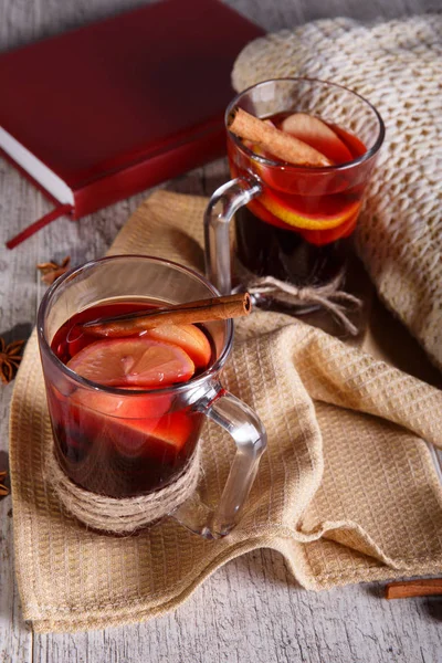 Tarçın ve kırmızı kitap üzerinde hafif bir arka plan üzerinde bir eşarp ile limonlu çay. Sıcak içecekler. Rahat ev atmosfer.