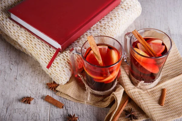 Tarçın ve kırmızı kitap üzerinde hafif bir arka plan üzerinde bir eşarp ile limonlu çay. Sıcak içecekler. Rahat ev atmosfer.