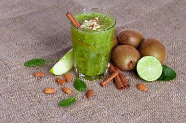 Bir yığın bir doğal kivi ve kireç görünümünü yukarıda hafif kahverengi kumaş arka plan üzerinde ikiye böldüm. Tropikal meyve ve rendelenmiş badem bir tabloda bir sağlıklı güler yüzlü. Kopya alanı.