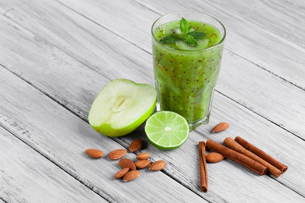 Kivi, elma ve kireç organik içki dolu bir cam üstten görünüm gri bir ahşap zemin üzerinde. Yeşil elma ve Ekşi limon bir masa üzerine ikiye böldüm. Tarçın ve badem yakınındaki bir kompozisyon.