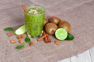 Bir yığın bir doğal kivi ve kireç yukarıdan bir görünümü gri bir ahşap zemin üzerine hafif kahverengi kumaş üzerinde ikiye böldüm. Tropikal meyve ve rendelenmiş badem bir tabloda bir sağlıklı güler yüzlü.