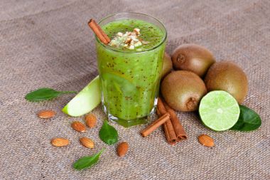 Bir yığın bir doğal kivi ve kireç görünümünü yukarıda hafif kahverengi kumaş arka plan üzerinde ikiye böldüm. Tropikal meyve ve rendelenmiş badem bir tabloda bir sağlıklı güler yüzlü. Kopya alanı.