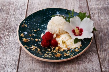 Vanilyalı dondurma ile nane ve güzel çiçek. Bir kase dondurma ve pembe ahududu ahşap arka plan üzerinde. Soğuk Yaz aperatifler.