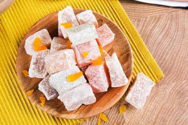 Bir masa lambası arka planda sarı kumaş üzerinde toz, renkli lokum dolu bir tabak yakın çekim resmin. Hafif bir aperatif için egzotik meyveli marmelat. Gurmeler için güzel Doğu tatlılar.