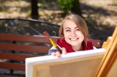 Kadın sanatçı sonbahar parkta bir resim boyama.