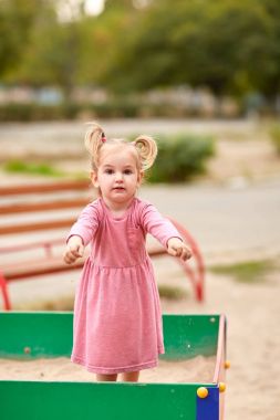 Bir kum içinde pembe elbiseli küçük kız.