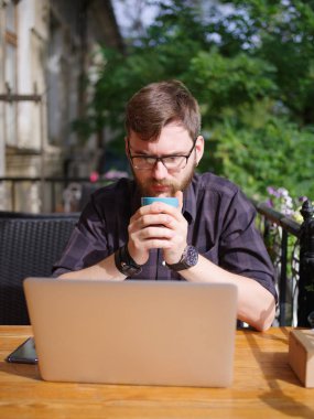 Bir genç sakallı adam onun laptop kullanarak bir kafede oturuyor.