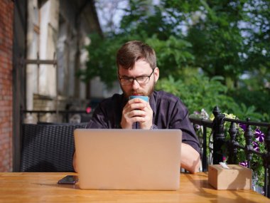 Bir genç sakallı adam onun laptop kullanarak bir kafede oturuyor.