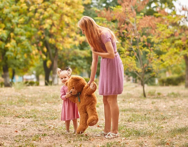 Giovane madre con figlia in piedi e orso nel parco — Foto Stock