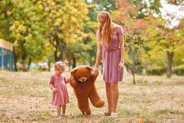 Giovane madre con figlia in piedi e orso nel parco — Foto Stock