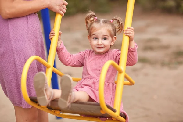Schönes kleines Mädchen in rosa auf einer Schaukel. — Stockfoto