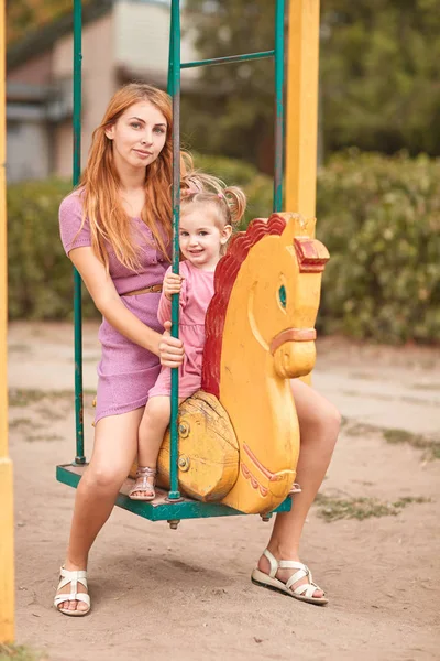 Mutter und Tochter auf einer Schaukel in rosa. — Stockfoto