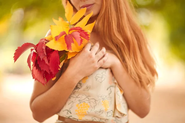 Дівчина в білій сукні з осіннім листям в руках — стокове фото