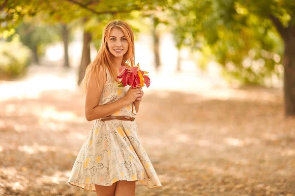 Menina em vestido branco com folhas de outono nas mãos — Fotografia de Stock