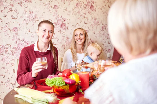 Beautiful girls and baby boy sitting at the festive table on a home background. Family smiling at Christmas dinner. — Stock Photo, Image