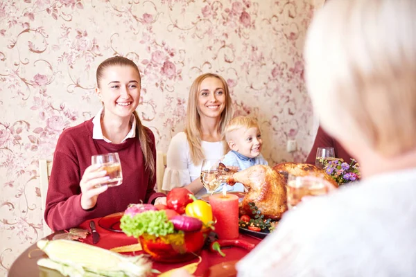 Beautiful girls and baby boy sitting at the festive table on a home background. Family smiling at Christmas dinner. — Stock Photo, Image