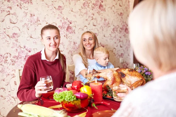 Beautiful girls and baby boy sitting at the festive table on a home background. Family smiling at Christmas dinner. — Stock Photo, Image