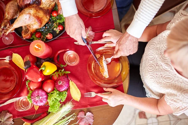 Close-up old man serving roasted turkey on a table background. Thanksgiving dinner. Traditional festive food concept. — Stock Photo, Image