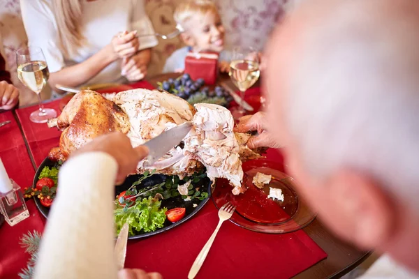 Man cutting roasted turkey on a table background. Family enjoying autumn holidays. Thanksgiving dinner concept. — Stock Photo, Image