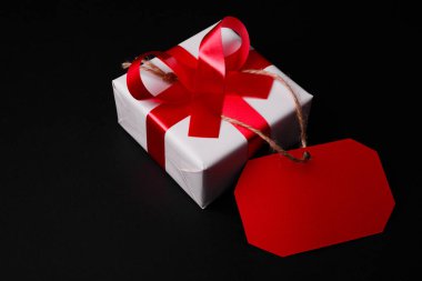 Kırmızı etiketi Close-Up beyaz hediye kutusu siyah bir zemin üzerine kırmızı kurdele ile bağlı olduğu.