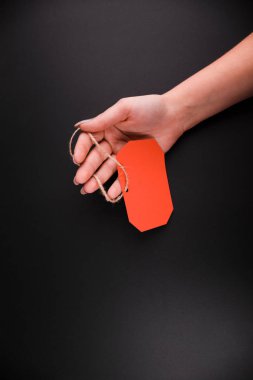 Siyah arka plan üzerinde kırmızı bir etiket satış tutan eller Close-Up.