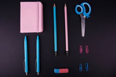 Yakın çekim dikey konum mavi ve pembe ofis, lastik bant yatay konumda siyah bir arka plan, üstten görünüm.