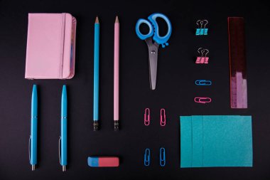 Siyah bir zemin üzerine mavi ve pembe mahkeme close-up. Yukarıdan görüntüleyin. Makas, kalem, kalem, kağıt üzerinde bir tablo.