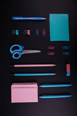 Siyah bir zemin üzerine mavi ve pembe mahkeme close-up. Yukarıdan görüntüleyin. Makas, kalem, kalem, kağıt üzerinde bir tablo.