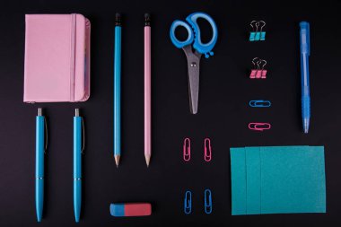 Siyah bir zemin üzerine mavi ve pembe mahkeme close-up. Yukarıdan görüntüleyin. Makas, kalem, kalem, kağıt üzerinde bir tablo.