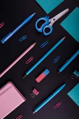 Siyah bir zemin üzerine mavi ve pembe mahkeme close-up. Yukarıdan görüntüleyin. Makas, kalem, kalem, kağıt üzerinde bir tablo.