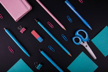 Siyah bir zemin üzerine mavi ve pembe mahkeme close-up. Yukarıdan görüntüleyin. Makas, kalem, kalem, kağıt üzerinde bir tablo.