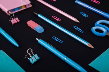 Siyah bir zemin üzerine mavi ve pembe mahkeme close-up. Yukarıdan görüntüleyin. Makas, kalem, kalem, kağıt üzerinde bir tablo.