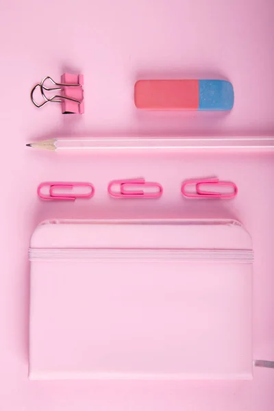 A close-up of a blue and pink office on a bright pink background. View from above. Blue and pink office. A lot of school objects.