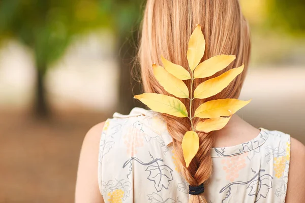 Güzel kızıl saçların close-up bir genç kız kıvrımlı kuru sonbahar yaprakları.