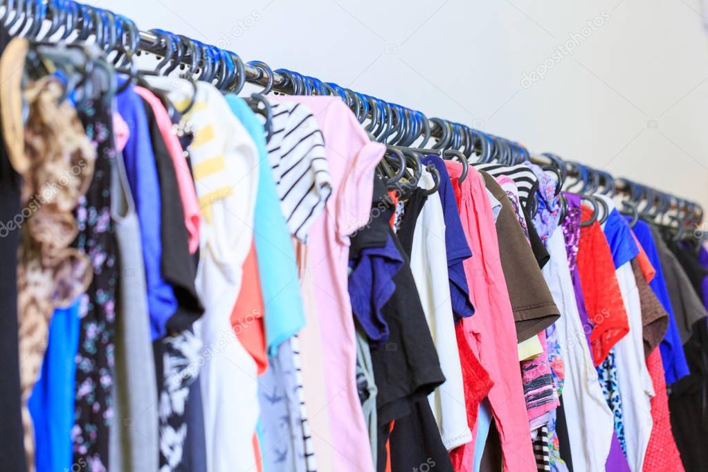 Colorful bright clothes on the shelves in the store on a white background. Shopping concept.