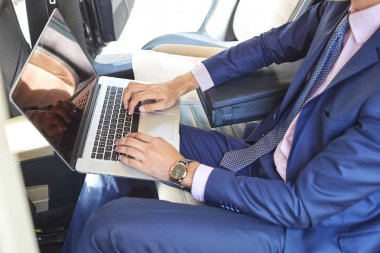 Bir arabanın arka koltuğunda çalışmak için bir dizüstü bilgisayar kullanan bir genç işadamı Close-Up.