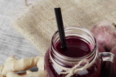 Op görünüm bir çanta ve gri bir arka plan üzerinde siyah saman bir mason kavanoza beetroots suyu. Pancar ve zencefil içecek, yakın çekim yakın. Sebze ve içecekler sağlıklı kahvaltı için.