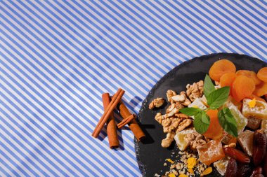 Çizgili Kumaş arka plan üzerinde bir tabakta üstten görünüm besleyici şekerlemeler maddeler. Hafif kahverengi ceviz, taze nane ve tarçın ile pudra şekeri Türk lokumu. Kopya alanı.