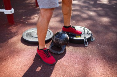 güçlü delikanlı ile seksi vücut egzersizleri kendi ayakları üzerinde yapıyor. adam parkta ayaklarıyla ağırlık kaldırıyor.