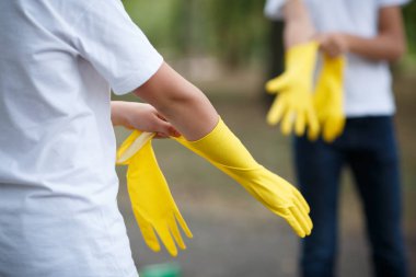 Açık havada temizlik takım çalışması. Çevre koruma. Portre portre kırpılmış. Başlarken başlamış temizlik. Sarı lastik Temizleme eldiven portre. Yetimhane kavramı. Takım yardım.